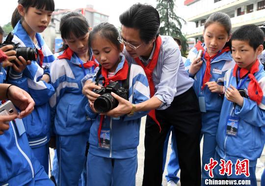 图为福建省摄影家协会主席潘朝阳向摄影希望小学学生讲解相机使用方法。　张斌 摄