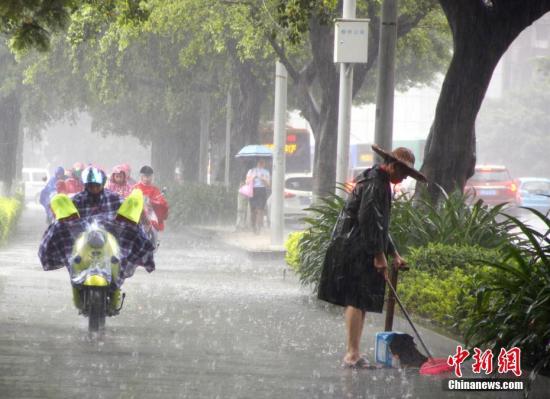 资料图：6月16日，广西柳州市遭暴雨侵袭，一名清洁工在雨中扫地。 记者 朱柳融 摄