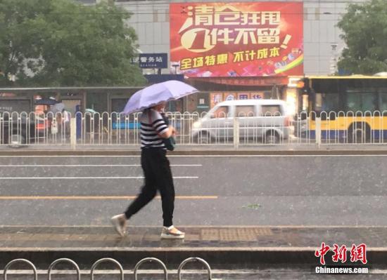 6月23日清晨，北京市民冒雨出行。 记者 富宇 摄