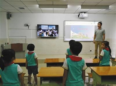 学生们通过远程在线教育系统与海口市滨海第九小学的学生一起上音乐课。