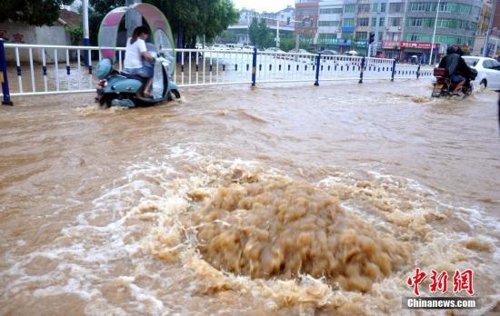 江西省瑞昌市黄金北路的两处下水道井盖被暴雨冲开，积水喷涌而出。魏东升 摄