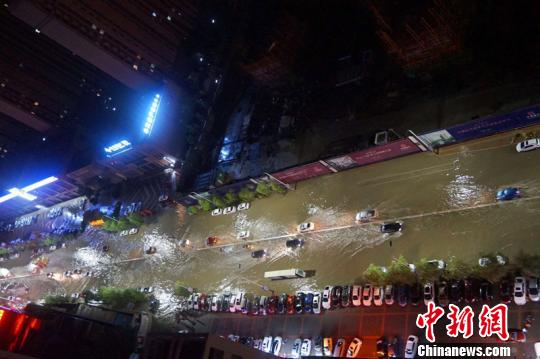 狂风暴雨下，汽车在街道积水中艰难前行。　李岩 摄